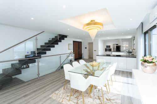 a dining room and kitchen with a glass table and white chairs at Villa Andrade Ocean View in Funchal