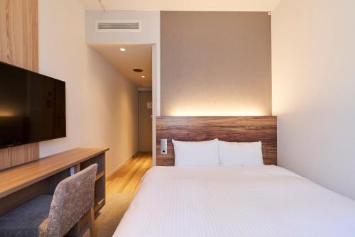 a hotel room with a bed and a flat screen tv at Hotel Global View Hachinohe in Hachinohe