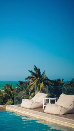 a pool with two beds and a palm tree at Mero Mero Hotel in El Cuyo