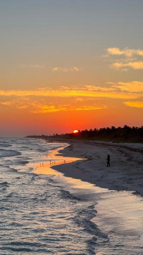 a person walking on the beach at sunset at Mero Mero Hotel in El Cuyo