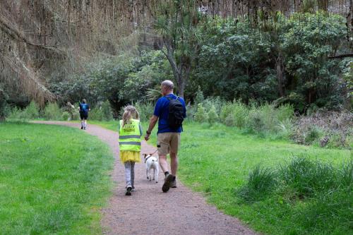 a man and a girl walking a dog on a path at Fantail Haven in Kinloch