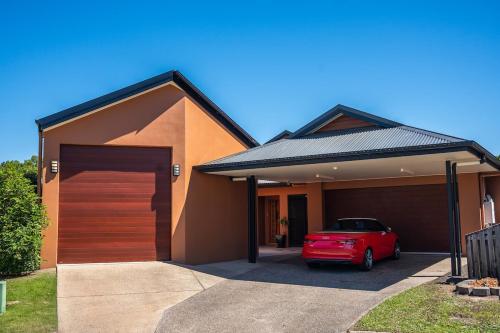 a red car parked in front of a garage at Lake House, stroll to beach & cafes- Pets Welcome in Trinity Beach