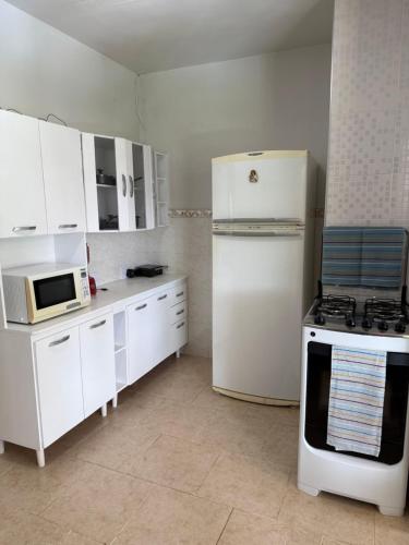 a kitchen with white cabinets and a white refrigerator at Chalé das Margaridas em São Lourenço a 2km do Parque das Águas in São Lourenço