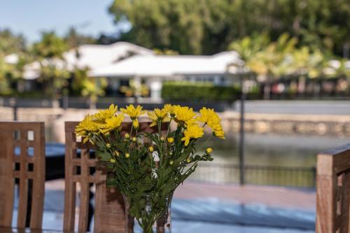 a vase of yellow flowers sitting on a table at Lake House, stroll to beach & cafes- Pets Welcome in Trinity Beach