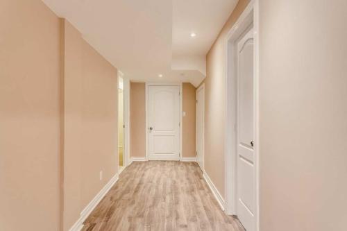 an empty hallway with a white door and wood floors at Nice and Cozy 2 Bed Bsmt Apt in Pickering