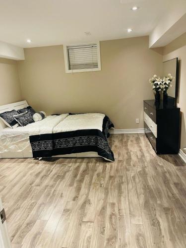 a bedroom with a bed and a wooden floor at Nice and Cozy 2 Bed Bsmt Apt in Pickering