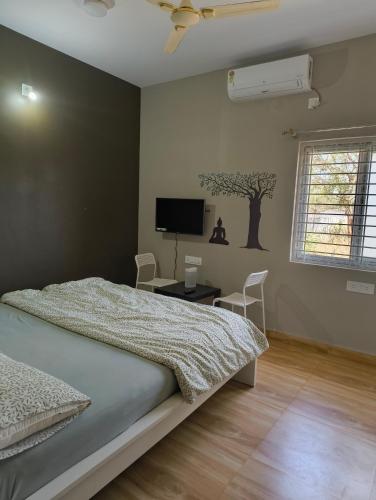 a bedroom with a bed and a tv on the wall at Jai Anjaneya Guesthouse in Devanahalli-Bangalore