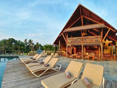 eine Gruppe von Liegestühlen auf einer Terrasse am Pool in der Unterkunft Tejaprana Bisma - CHSE Certified in Ubud