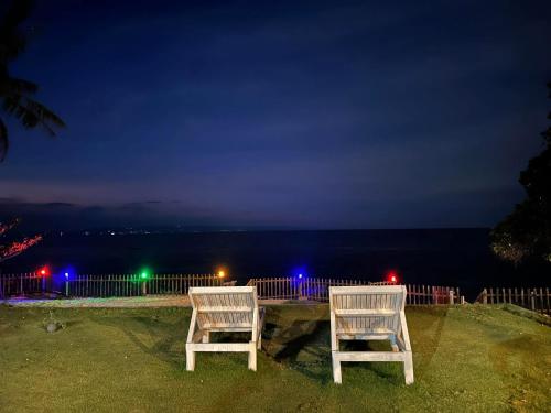 two chairs sitting on the grass near the ocean at night at Diamond De Siquijor Beach House in Siquijor