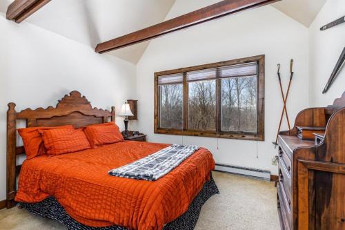 a bedroom with a bed with an orange comforter and a window at 4-Bedroom Townhouse in Beautiful Galena in Galena