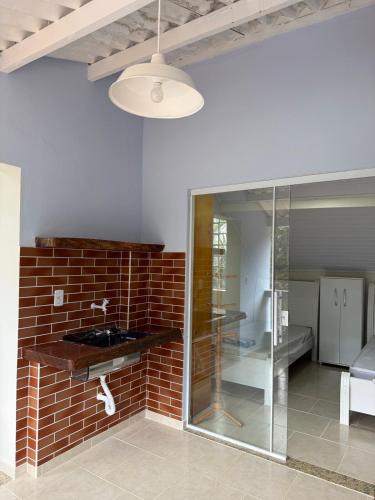 a room with a brick wall and a glass shower at Chalé das Hortênsias em São Lourenço a 2 km do Parque das Águas in São Lourenço