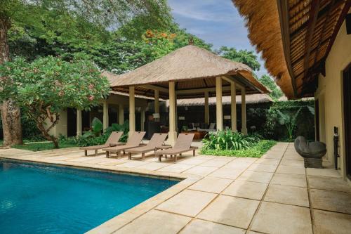 a resort with a pool and chairs and a pavilion at Kayumanis Sanur Private Villa and Spa in Sanur