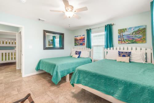 Un dormitorio con dos camas y un ventilador de techo. en Boogie Board Bungalow - Pet Friendly PRIVATE POOL 2, en Port Aransas