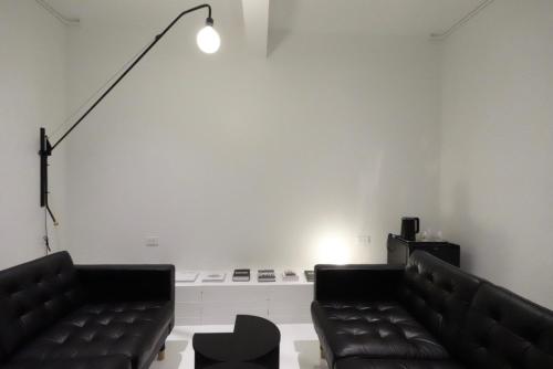 a living room with two black leather couches and a lamp at Dear Sunday Hometel Bangkok in Bangkok