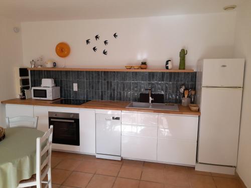 une cuisine avec des armoires blanches et un réfrigérateur blanc dans l'établissement Le Mazet des Jasmins, à Gordes