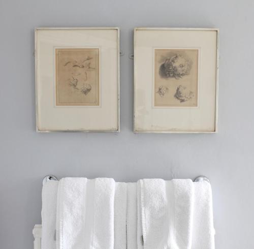 two framed pictures on a white wall with towels at Black Lion Hotel in Little Walsingham