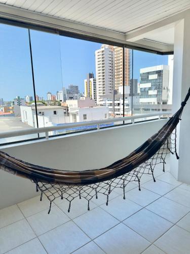 a hammock in a room with a view of a city at Cobertura duplex 3 quartos, centro, terraço e churrasqueira, ideal para família, acesso por escadas in Torres