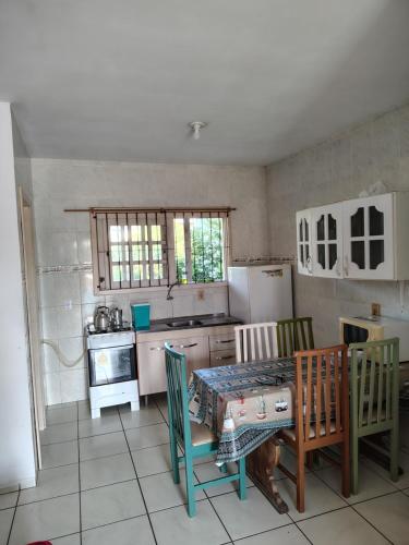 a kitchen with a table and chairs and a kitchen with a refrigerator at Pousada e Residencial Linda in Capão da Canoa
