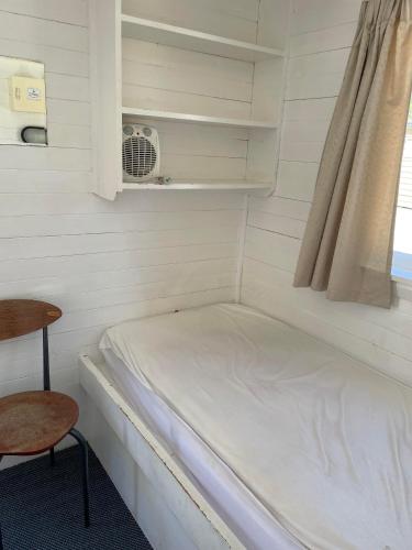 a small room with a bed and a chair at Hanmer Springs Forest Camp Trust in Hanmer Springs