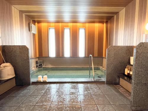 a bathroom with a bath tub with a window at Bell's Inn Maebashi in Maebashi