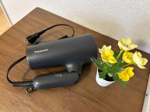 a black hair dryer next to a vase of flowers at Shinjuku Tokyo Holiday Hotel in Tokyo