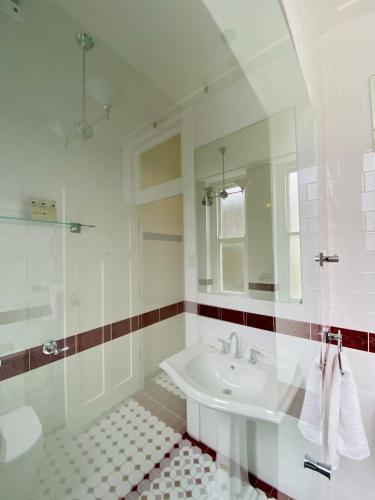 a white bathroom with a sink and a mirror at Carrington Hotel in Katoomba