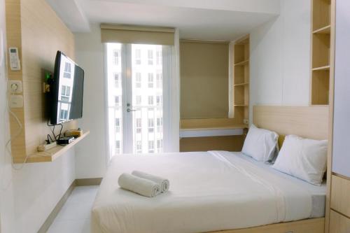 a bedroom with a white bed and a window at New and Nice Designed Studio at Tokyo Riverside PIK 2 Apartment By Travelio in Rawalembang