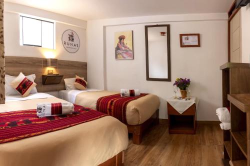 a hotel room with two beds and a mirror at Runas Inn Machupicchu in Machu Picchu