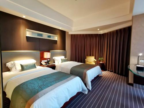 a hotel room with two beds and a desk at Kunming Haitian Hotel in Kunming