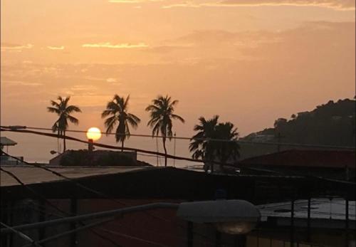 a sunset over the water with palm trees in the background at Casa central in San Juan del Sur