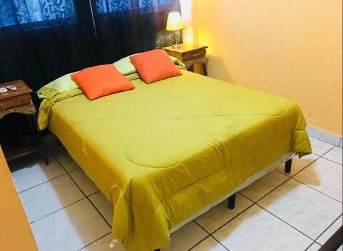 a yellow bed with two orange pillows on it at Casa central in San Juan del Sur