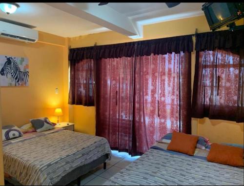 a bedroom with two beds and red curtains at Casa central in San Juan del Sur