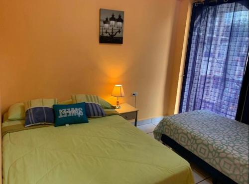 a bedroom with a green bed and a window at Casa central in San Juan del Sur
