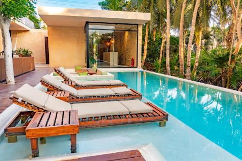 a group of lounge chairs and a swimming pool at Luxury Romantic Getaway - 1 Bedroom - Steps from the Beach - Bahia Tankah Tulum in Tulum