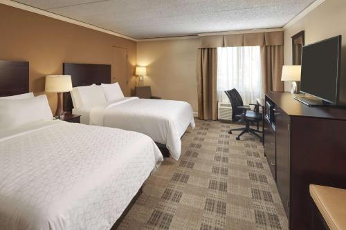 a hotel room with two beds and a flat screen tv at Wyndham Executive Center Columbia in Columbia