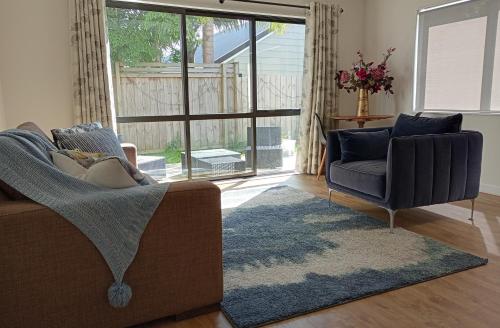 ein Wohnzimmer mit zwei Stühlen und einer Couch in der Unterkunft Orewa Beachfront Apartment in Orewa