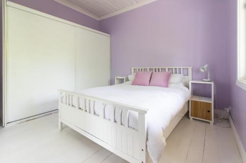 1 dormitorio con cama blanca y paredes moradas en Cosy, historic & affordable 2-bed apartment - 5kms from Castlemaine, 2kms from Calder, en Barkers Creek