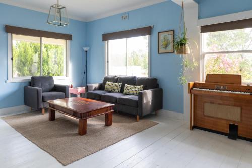 a living room with a couch and a piano at Cosy, historic & affordable 2-bed apartment - 5kms from Castlemaine, 2kms from Calder in Barkers Creek