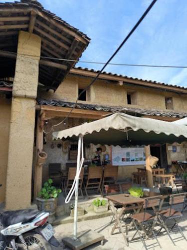 a patio with a table and an umbrella in front of a house at Long Cổ Trấn Homestay in Dồng Văn