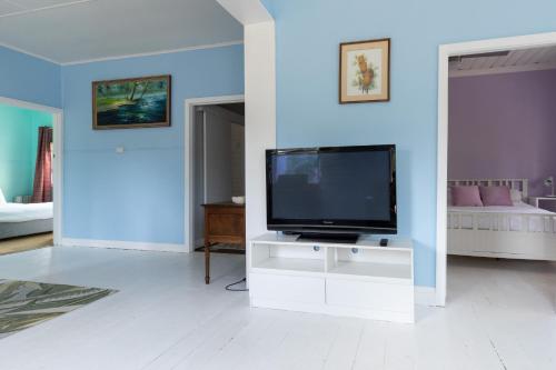 a living room with a flat screen tv on a white cabinet at Cosy, historic and affordable entire cottage - 3 bedroom, 2 bathroom - 5kms from Castlemaine, 2kms from Calder in Barkers Creek