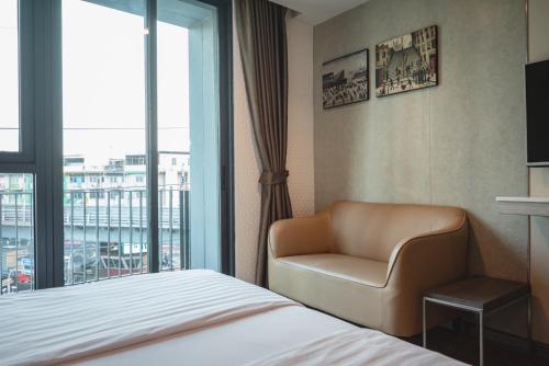 a hotel room with a bed and a chair and a window at BB House Khlongtan in Bangkok