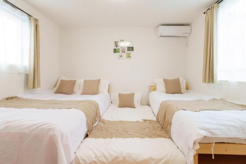 three beds in a room with white walls and windows at 福吉屋 in Tokyo