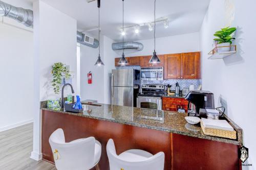 a kitchen with a counter with white chairs at The Stallion #209 - Walk to Museums, Luxe Loft with free gated & covered parking in Memphis