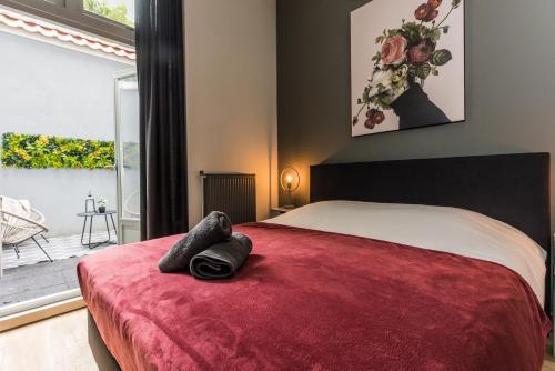 a bedroom with a bed with a red blanket at Haya Historic - Rosé in The Hague