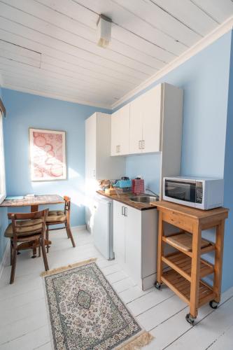 a kitchen with white cabinets and a table with a microwave at Cosy, historic and affordable entire cottage - 3 bedroom, 2 bathroom - 5kms from Castlemaine, 2kms from Calder in Barkers Creek
