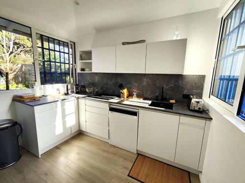 - une cuisine blanche avec des armoires et des fenêtres blanches dans l'établissement Villa rénovée 4 ch. à 50m du Bassin avec terrasse et jardin, WIFI, parking - FR-1-736-54, à Lège-Cap-Ferret