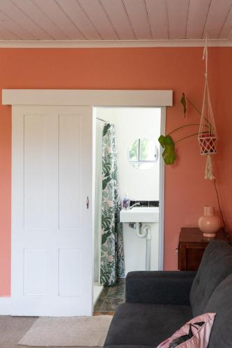 a living room with orange walls and a white door at Cosy and historical one bedroom apartment, 5kms from Castlemaine, 2 kms from the Calder in Barkers Creek