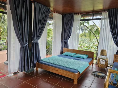 a bed with blue pillows in a room with windows at Phú Điền Homestay in Tân Phú