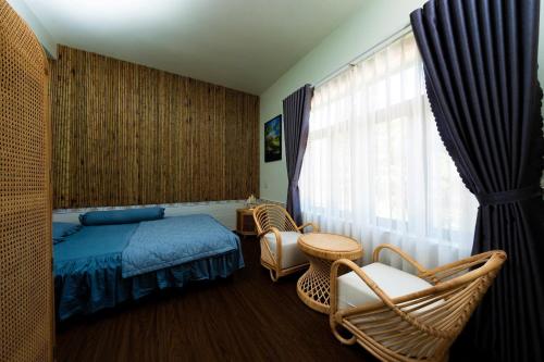 a bedroom with a bed and chairs and a window at Phú Điền Homestay in Tân Phú