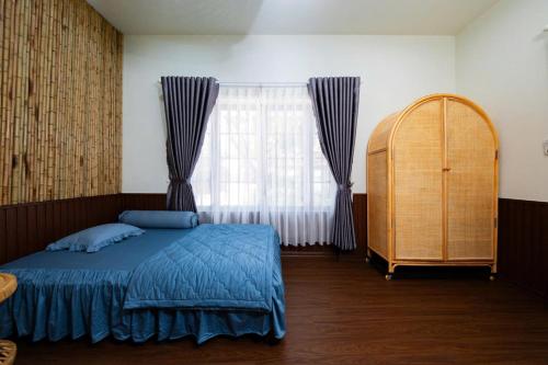 a bedroom with a blue bed and a window at Phú Điền Homestay in Tân Phú